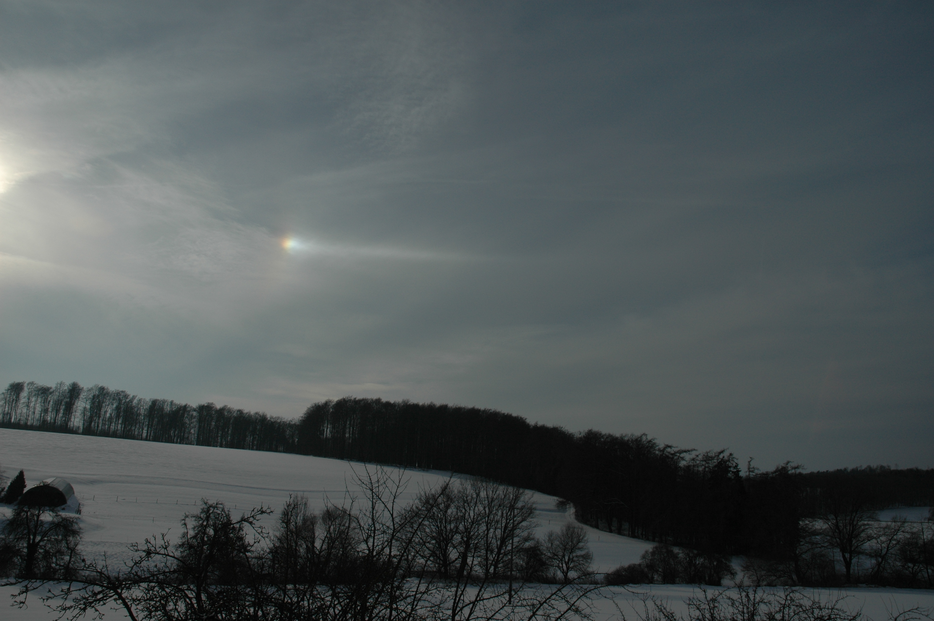 Beschweifte 22°-Nebensonne mit Spektralfarben am (cirrusbedeckten) Winterhimmel
